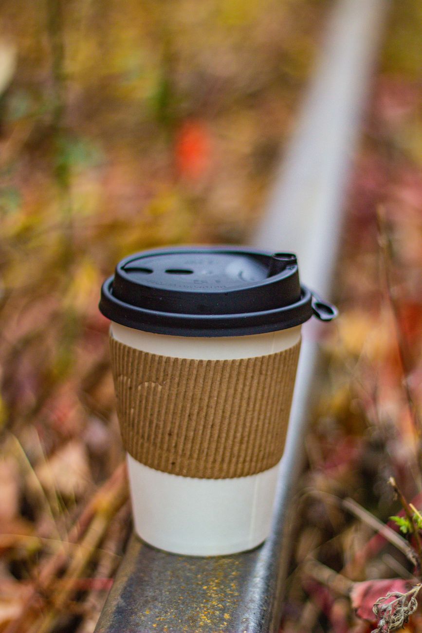 a cup of coffee on a metal railing