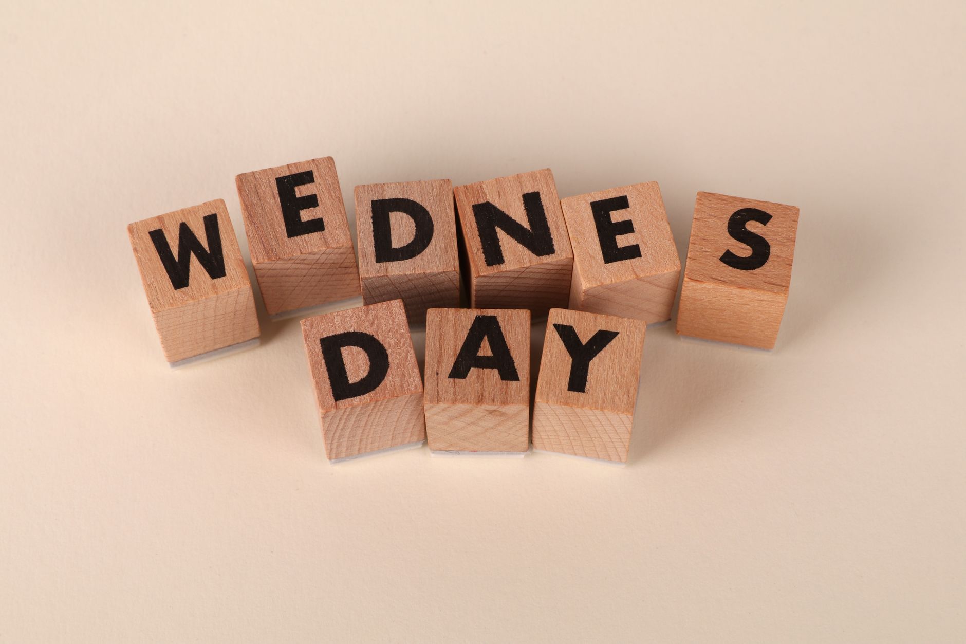 wooden blocks spelling wednesday on beige background